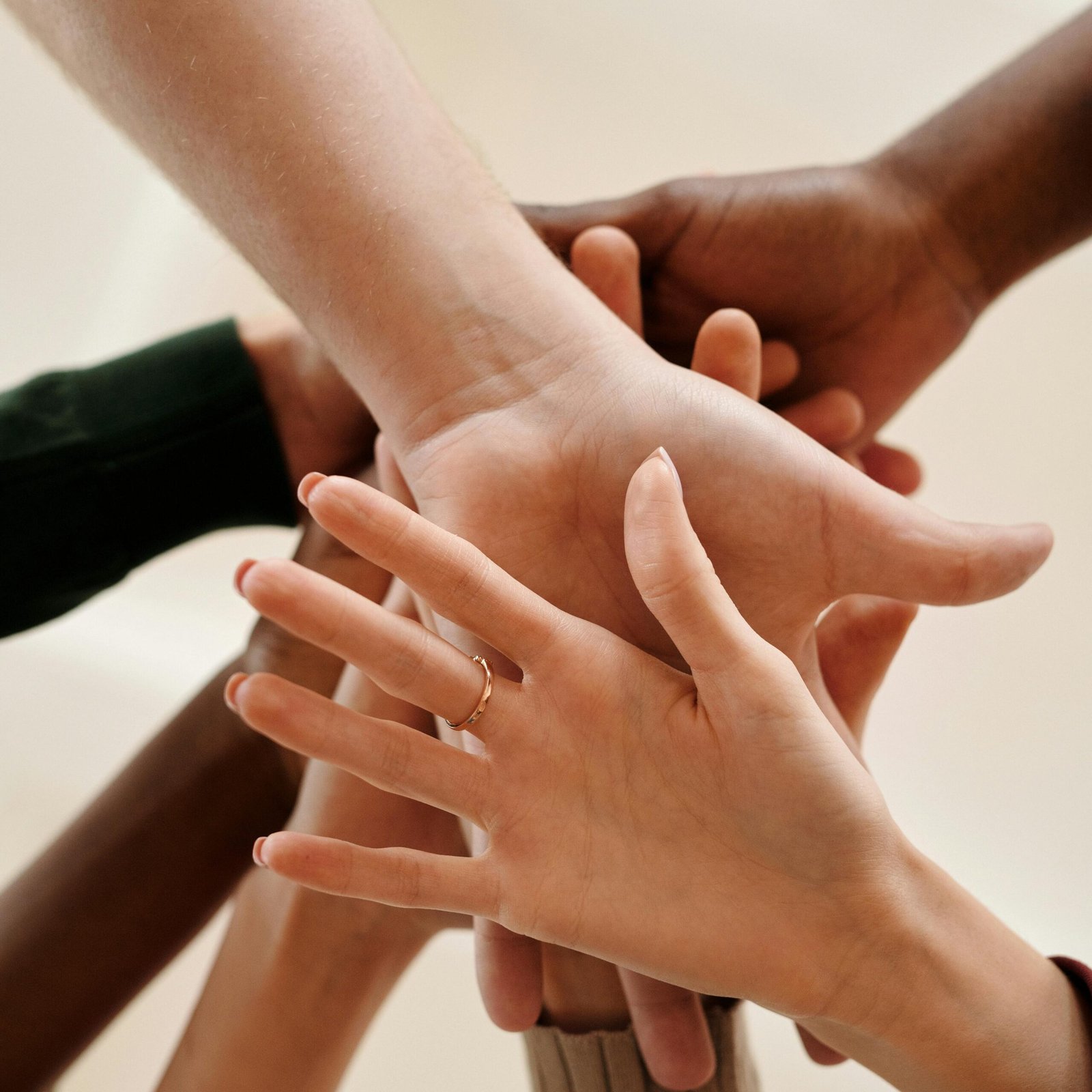 A close-up of diverse hands joined together symbolizing teamwork, cooperation, and unity indoors.